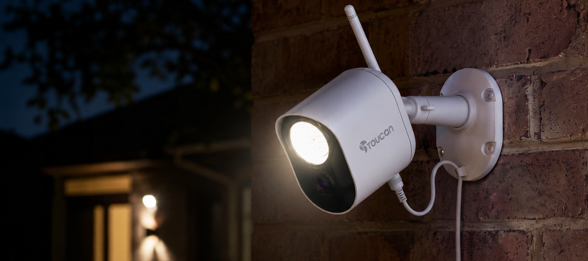 Outdoor security camera mounted beside a home after dark